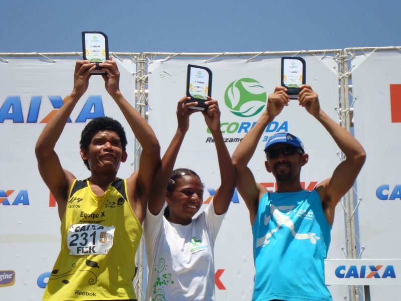 Imagem com Ailton, Mariane e Adalto, todos DVs, erguendo seus troféus.