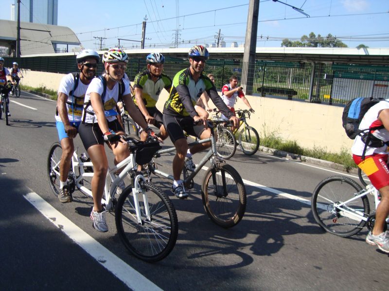 Imagem mostra Weimar (condutor) e Wallace (DV); Renata (condutora) e Adauto (DV), pedalando pelas ruas de São Paulo