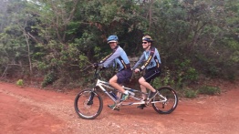 Na imagem, Ricardo sendo conduzido pelo Mauro (vulgo, cueca virada) em uma tandem e ao fundo, uma mata verde, linda! Ambos, sorrindo muito.